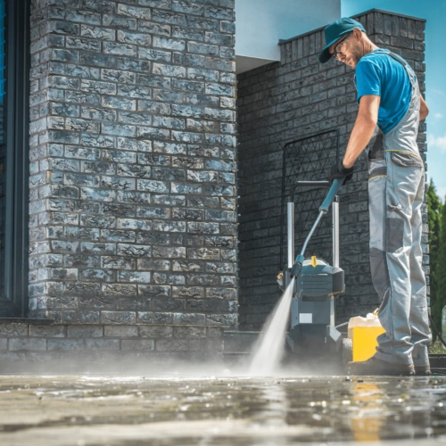 A man cleaning a sidewalk with a pressure washer.