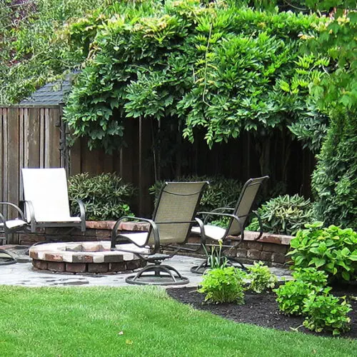 A small backyard with a fire pit and chairs.