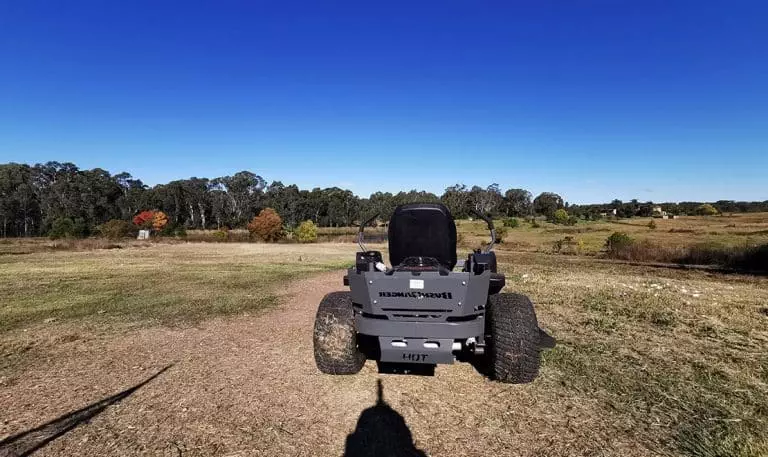 A black atv parked in a field with a blue sky.